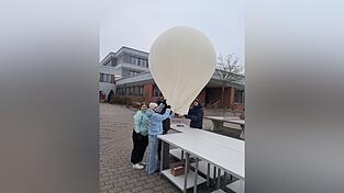 Die Sch&uuml;ler Verena (v. l.), Hannah und Peter haben mit Unterst&uuml;tzung von Lehrer Andreas Kelbel am zweiten Weihnachtsfeiertag den Ballon im Pausenhof des Gymnasiums gestartet.