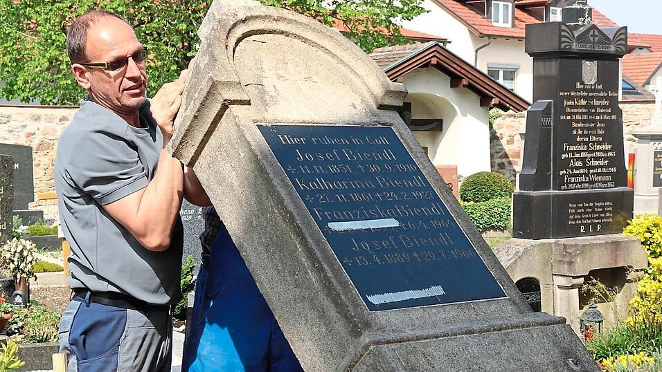 Der Steinmetz legt den Grabstein vorsichtig um. Der Steinmetz legt den Grabstein vorsichtig um.