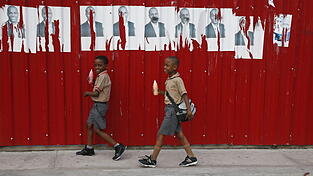 Zwei Kinder schlendern am 21. Januar 2016 in Port-au-Prince auf Haiti vor dem Propaganda-Plakat des Pr&auml;sidentschaftskandidaten Jovenel Moise. Der aktuelle Pr&auml;sident Michel Martelly gab seine Zustimmung zur zweiten Runde der Pr&auml;sidentschaftswahlen am kommenden Sonntag, den 24. Januar.