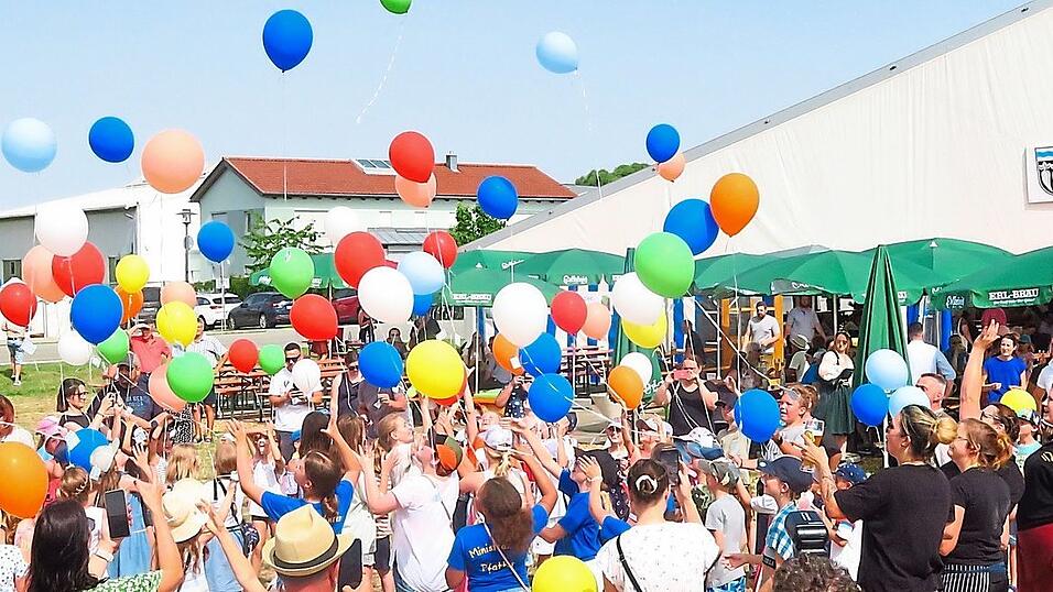 Bunte Luftballons gr&uuml;&szlig;en aus dem Jubeldorf.
