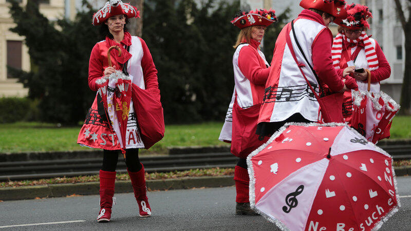 Karnevalisten stehen am 07.02.2016 in K&ouml;ln (Nordrhein-Westfalen) bei den K&ouml;lner Schull- und Veedelsz&ouml;ch (Schul- und Viertelsz&uuml;ge) mit Schirmen auf der Strasse. In einigen St&auml;dten halten sich die Jecken die Entscheidung offen, ob sie den Rosenmontagszug wegen eines Sturmtiefs absagen.