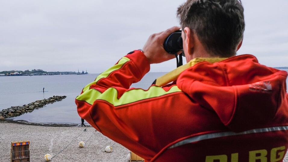 Ein DLRG-Mitarbeiter schaut durch ein Fernglas. Ein DLRG-Mitarbeiter schaut durch ein Fernglas.