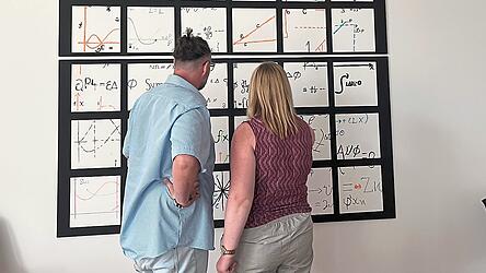 Jakob und Anja vor dem von Mitarbeitern geschaffenen Gemeinschaftskunstwerk, dem Theoreme der Mathematikerin Emmy Noether zugrunde liegen.