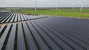 Windkraftanlagen drehen sich hinter Solaranlagen. Windkraftanlagen drehen sich hinter Solaranlagen.