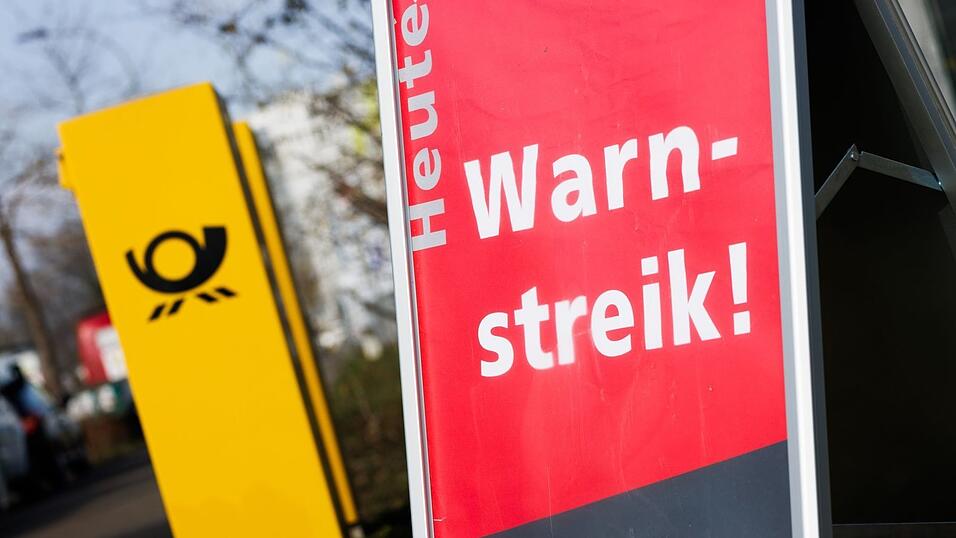 Ein Warnstreik-Schild bei einem Post-Standort, daneben ein Briefkasten - im Ringen um einen Tarifabschluss haben Tausende Postler erneut die Arbeit niedergelegt.