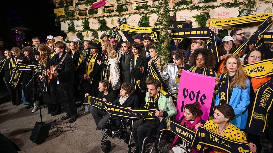 Mit Schals und Schildern haben Prominente an einer Protestaktion von SOS Humanity teilgenommen.