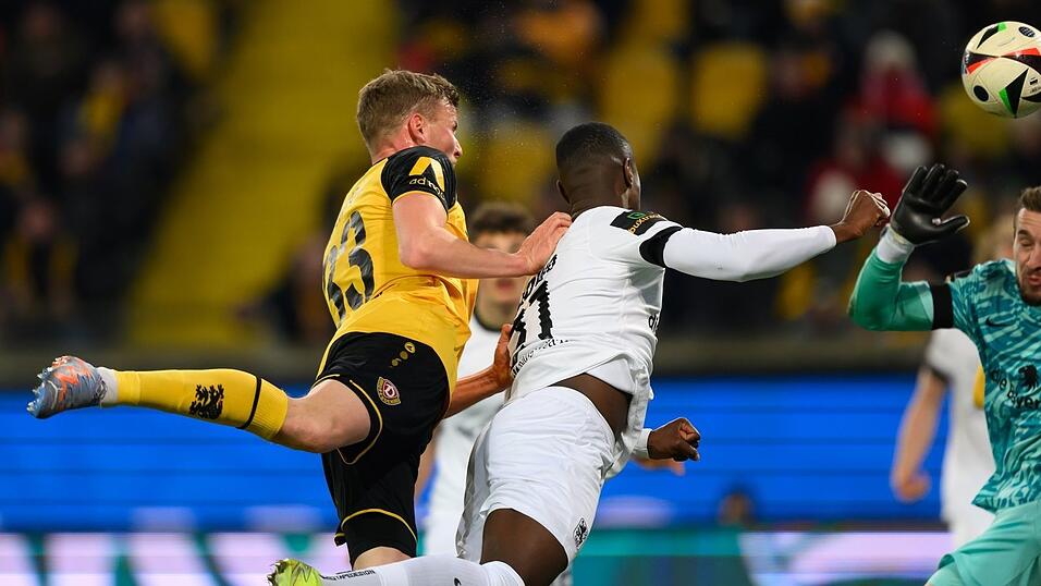 Dynamos Christoph Daferner (l) erzielt gegen Münchens Leroy Kwadwo und Torwart Marco Hiller das Tor zum 2:1.