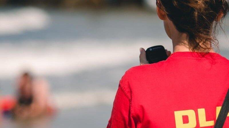 Eine DLRG-Mitarbeiterin steht am Wasser. Eine DLRG-Mitarbeiterin steht am Wasser.