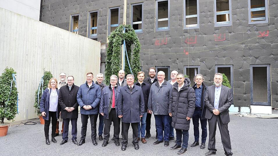 Beim Richtfest dabei: Bayerns Bauminister Christian Bernreiter (Mitte) vor der Richtkrone mit (v.l.) Christiane Hofer, derzeit stellvertretende Leiterin der JVA Amberg/Weiden und desiginierte Leiterin der JVA Passau, Passaus Oberb&uuml;rgermeister J&uuml;rgen Dupper, MdL Stefan Meyer, MdL Josef Heisl, Prof. Dr. Gerhard Waschler, MdL Josef Zellmeier, Vorsitzender des Anstaltsbeirats, JVA-Leiter Marcus Hegele, MdL Toni Schuberl, MdL Tobias Beck, stv. Vorsitzender des Anstaltsbeirats, MdL Christian Lindinger, MdL Oskar Atzinger, Landrat Raimund Kneidinger, Architekt Ludwig Karl und Gerald Escherich, Bereichsleiter Hochbau am Staatlichen Bauamt Passau.