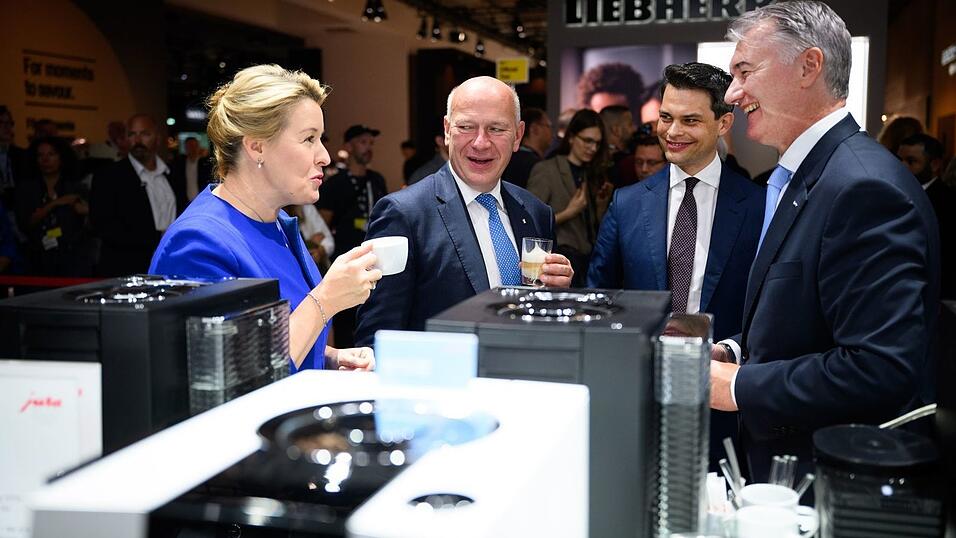 Wirtschaftssenatorin Franziska Giffey lässt sich gemeinsam mit dem Regierenden Bürgermeister Kai Wegner einen Espresso am Stand von Jura Elektrogeräte schmecken.