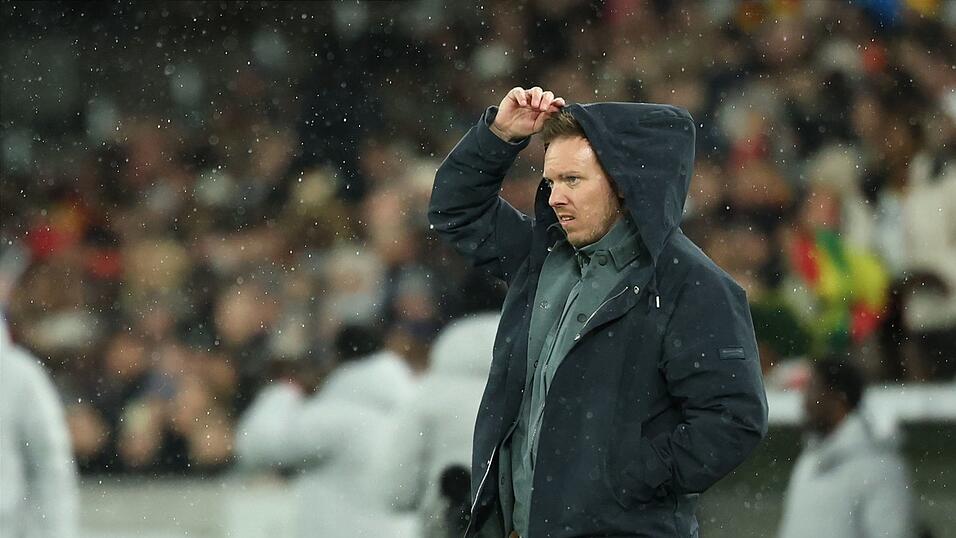 Julian Nagelsmann zieht sich im Regen eine Kapuze &uuml;ber den Kopf.