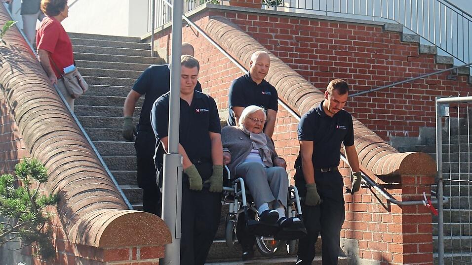 In Viererteams helfen Ehrenamtliche der Feuerwehr Vilsbiburg, die Teilnehmer der Wallfahrt hinauf und hinunter zu tragen