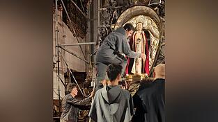 In den Monaten Mai und Oktober wird die Gottesmutter vom Mesnerteam bekleidet, hier legt gerade Bruder Jan vom Kloster Bogenberg Hand an. Im restlichen Jahr ist die gesamte Sandsteinfigur zu sehen.