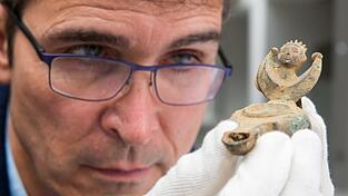 Augsburgs Stadtarchäologe Sebastian Gairhos betrachtet eine antike Öllampe, die vor wenigen Jahren in Bayerns ältestem Römerlager entdeckt wurde. (Archivbild) Augsburgs Stadtarchäologe Sebastian Gairhos betrachtet eine antike Öllampe, die vor wenigen Jahren in Bayerns ältestem Römerlager entdeckt wurde. (Archivbild)