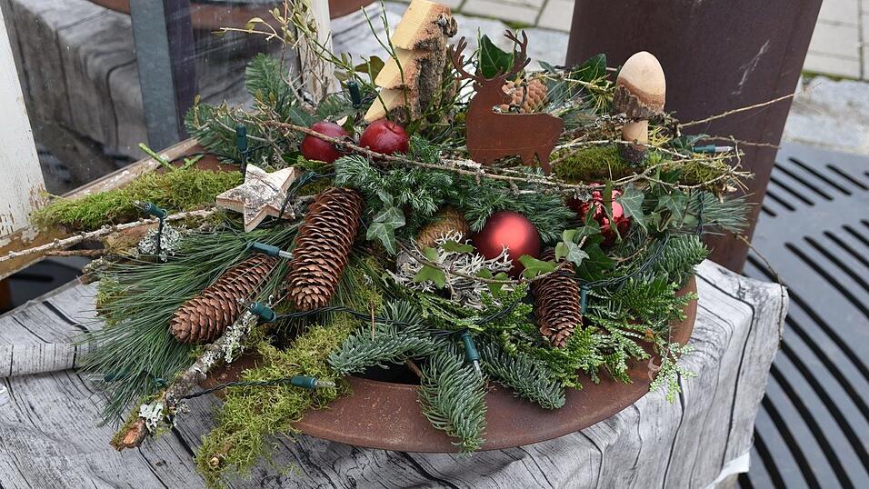 Viel Natur ist hier zu sehen. Edelrost, eine matte rote Glaskugel und Holzornamente schaffen Abwechslung. Der weihnachtliche Teller mit verschiedenem Ästen, Reisig und Moos ist auch mit einer Lichterkette beleuchtet.