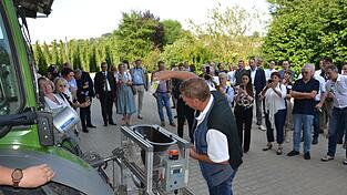 Unter den Augen von Staatskanzleichef Florian Herrmann (rechts im Hintergrund) füllt Florian Weihrauch ein Plastikfläschchen mit zirka 10.000 Raubmilben in den Trichter des an einem Traktor montierten Gebläses, das die Nützlinge zielgenau im Hopfengarten aussetzt, wo sie der Roten Spinne an den Kragen gehen sollen.