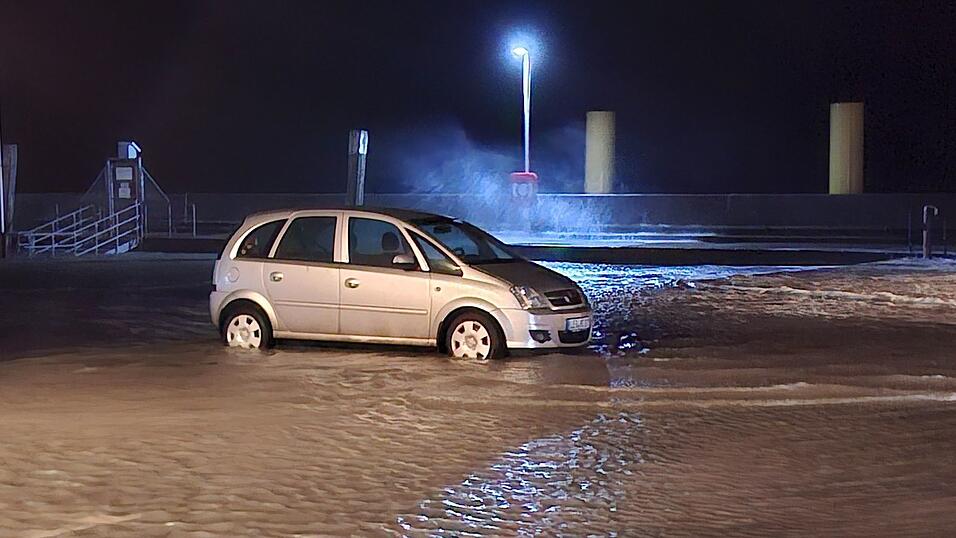 In Wilhelmshaven steht ein Auto auf einem überfluteten Parkplatz.