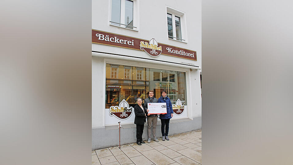 Irmgard Br&auml;u (l.) nimmt mit gro&szlig;er Freude dankbar den Spendenscheck &uuml;ber 13 500 Euro von Junior-Chef Michael Schifferl und Filialleiterin Elke Liebl vor der 'Gutes von gestern'-Filiale in der Bahnhofstra&szlig;e entgegen.
