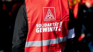 Ein Teilnehmer einer Kundgebung der IG Metall trägt eine rote Weste mit der Aufschrift 'Solidarität gewinnt!'. Ein Teilnehmer einer Kundgebung der IG Metall trägt eine rote Weste mit der Aufschrift 'Solidarität gewinnt!'.
