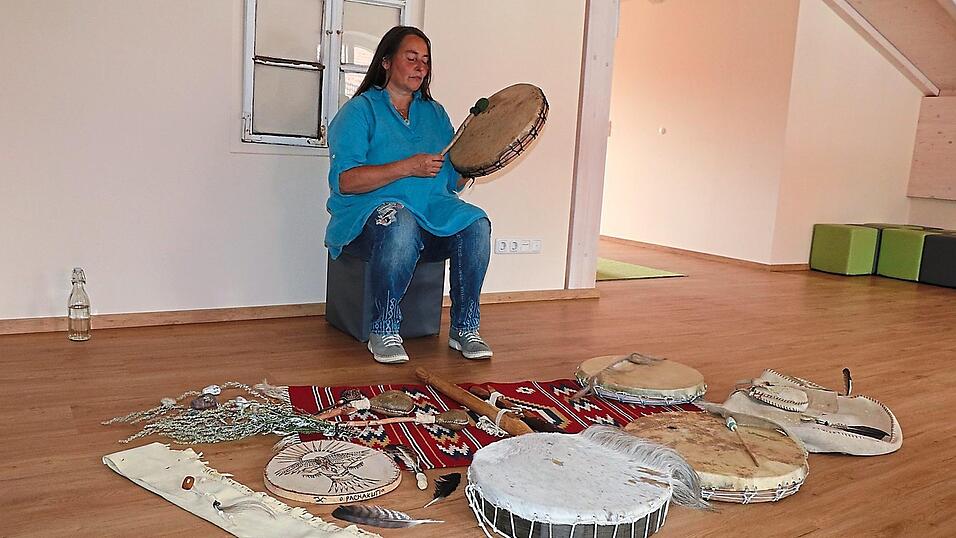 Bettina Lorenz, die sich als Schamanin White Wind Whisper nennt, bei einer Trommelreise; vor ihr weitere Trommeln, Fl&ouml;ten und andere Gegenst&auml;nde aus ihrer Werkstatt.