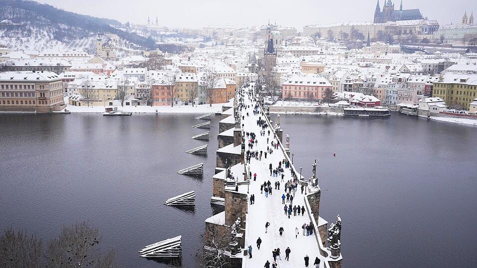 Menschen &uuml;berqueren die mittelalterliche Karlsbr&uuml;cke nach starkem Schneefall.
