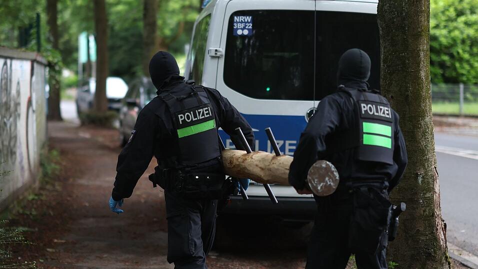 Polizisten tragen einen Rammbock. Polizisten tragen einen Rammbock.