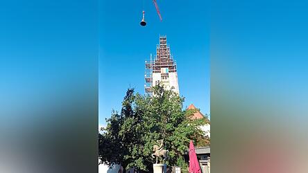 Beim Einheben schwebte die renovierte historische Tausend-Kilogramm-Glocke direkt über dem vom Straßkirchner Künstler Kasimir Boot gestalteten Postillion des Dorfbrunnens