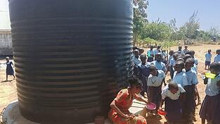 Eine Lehrerin verteilt Trinkwasser aus dem 5.000 Liter fassenden Tank, den die Ukunda-Hilfe mit Frischwasser auff&uuml;llen hat lassen.