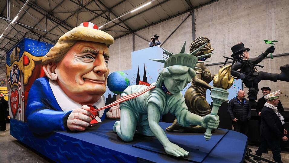 Einer der Wagen im Kölner Rosenmontagszug zeigt US-Präsident Donald Trump, der die Freiheitsstatue und die Justitia am Laufband führt.
