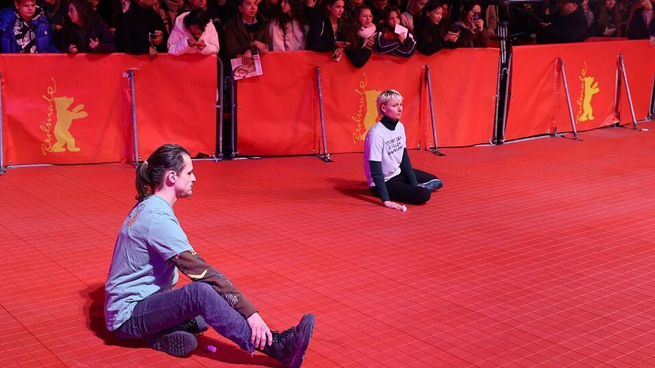 Eine Frau und ein Mann haben sich bei der Eröffnung der Berlinale auf dem roten Teppich festgeklebt. Eine Frau und ein Mann haben sich bei der Eröffnung der Berlinale auf dem roten Teppich festgeklebt.