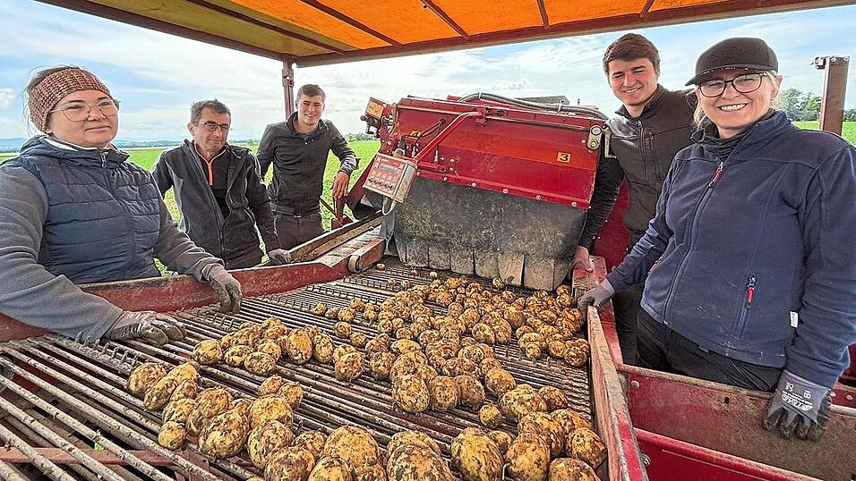 Familie Bayer und Mitarbeiter auf der gro&szlig;en Kartoffelerntemaschine.