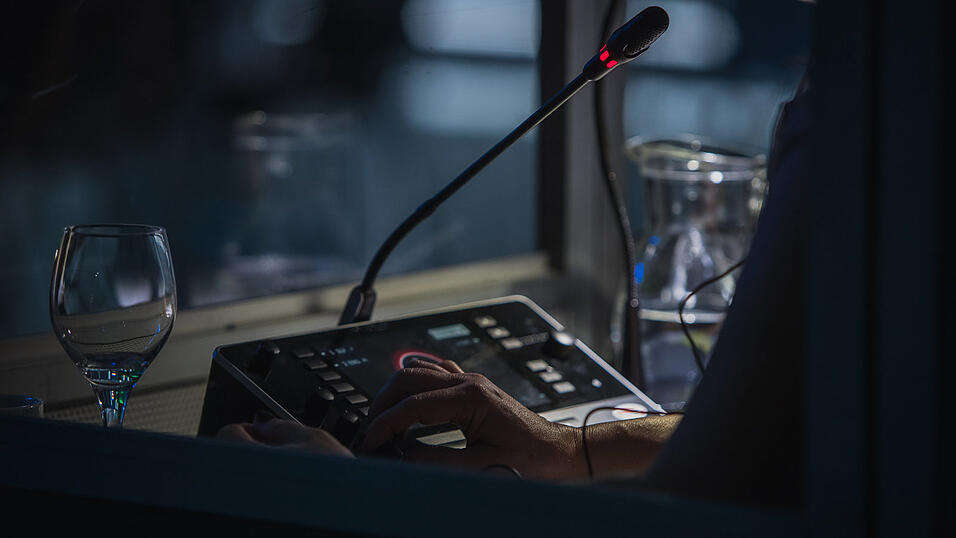 Vor dem Mikro hinter Glasscheiben in einer Kabine: So stellt man sich einen Dolmetscher vor.