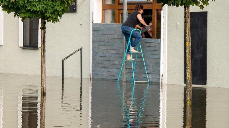 Zwei Personen dichten in Passau den Eingang eines Cafés mit einer speziellen Hochwassersperre ab, um das Gebäude vor dem Wasser der Donau zu schützen. Zwei Personen dichten in Passau den Eingang eines Cafés mit einer speziellen Hochwassersperre ab, um das Gebäude vor dem Wasser der Donau zu schützen.