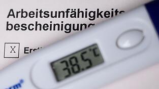 Ein Fieberthermometer liegt auf einer Arbeitsunfähigkeitsbescheinigung. Ein Fieberthermometer liegt auf einer Arbeitsunfähigkeitsbescheinigung.
