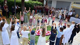 Die Kinder aus der Prozession versammelten sich rund um den Blumenteppich und beteten und sangen kr&auml;ftig mit.