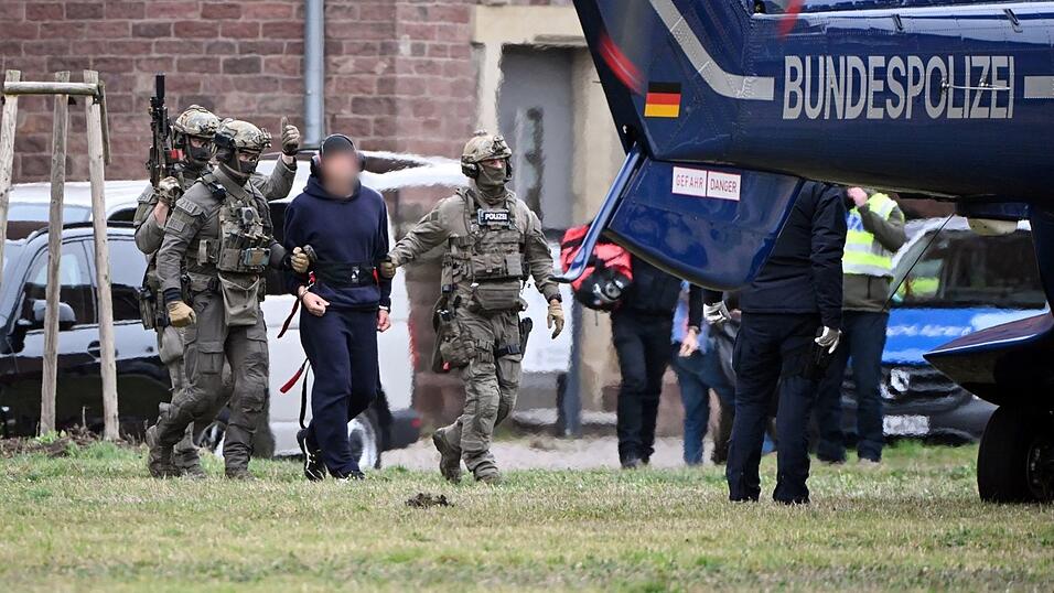 Eine Person wird von Polizeibeamten zu einem Hubschrauber gebracht. Eine Person wird von Polizeibeamten zu einem Hubschrauber gebracht.