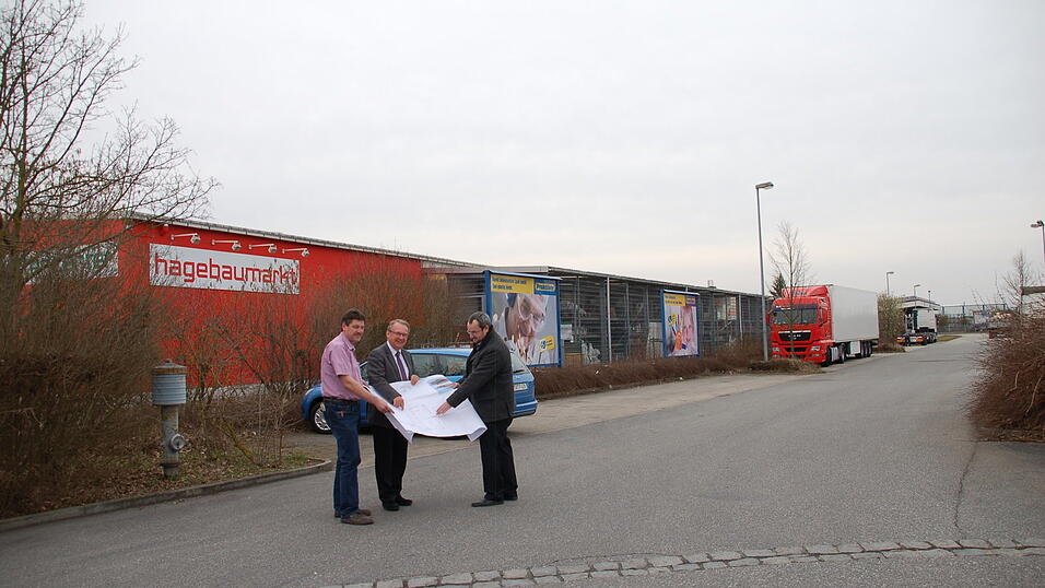 Diese Stra&szlig;e zwischen Hagebaumarkt und Praktiker-Immobilie muss f&uuml;r die Erweiterungspl&auml;ne verlegt werden. Das Bild zeigt (v.l.) Manfred Weber, den Leiter des Hagebaumarkts, Wolfgang Gural, Gesch&auml;ftsf&uuml;hrer der Betreibergesellschaft des Hagebaumarkts, sowie Architekt Hannes S&uuml;&szlig;, dessen Firma die Bauma&szlig;nahme als Generalunternehmer ausf&uuml;hrt.