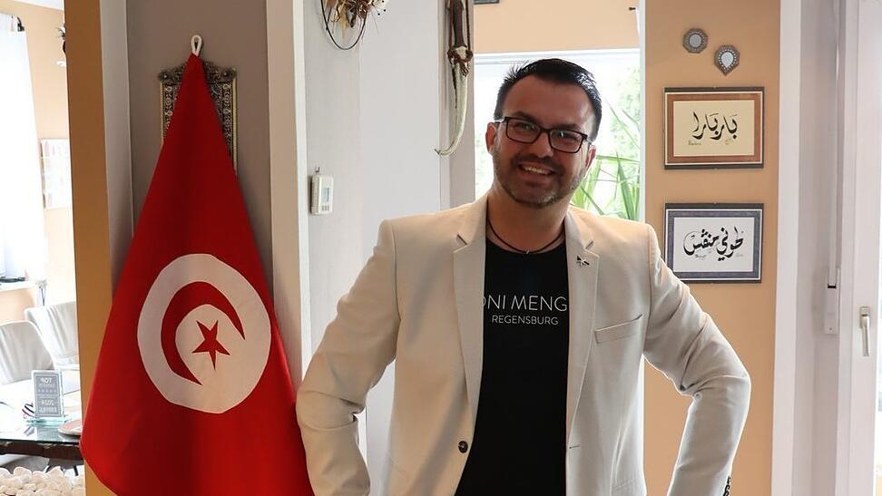 Neben der Nationalflagge h&auml;ngen auch Schriftst&uuml;cke aus Tunesien im Wohnzimmer von Toni Menges. Er sch&auml;tzt das Land und die Herzlichkeit seiner Bewohner. In wenigen Tagen steht die n&auml;chste Reise an.
