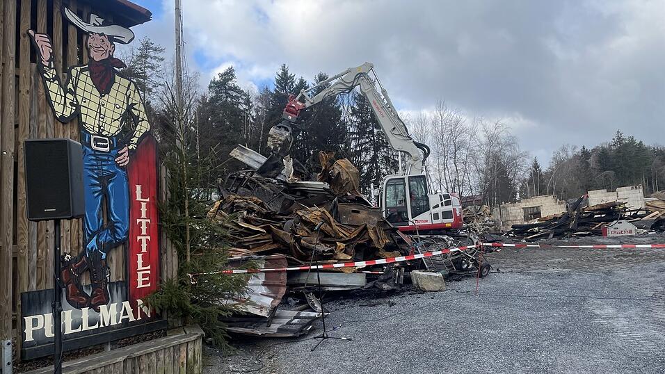 Bagger sortieren die verkohlten Überreste der Gebäude.