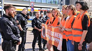 Teilnehmer eines Protestmarsches der Letzten Generation gehen um den Leipziger Ring.