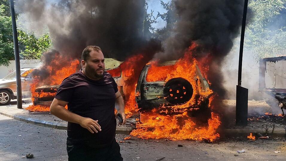 Ein Mann läuft vor brennenden Autos, die bei einem israelischen Luftangriff in der libanesischen Hafenstadt Sidon in Brand geraten sind. Ein Mann läuft vor brennenden Autos, die bei einem israelischen Luftangriff in der libanesischen Hafenstadt Sidon in Brand geraten sind.