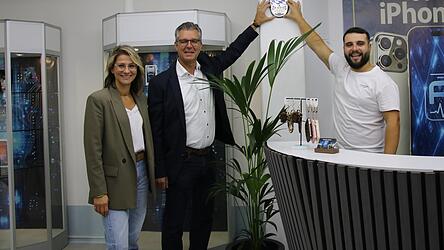 Kulturamtsleiterin Kathrin Tost und Bürgermeister Hans Schmalhofer (Mitte) wünschten Inhaber Nevres Mujagic viel Erfolg mit seinem Laden. Zur Eröffnung gab es außerdem ein Original Plattlinger Stadtwappen.