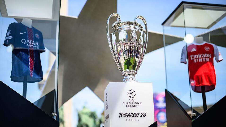Der Pokal der Champions League steht zwischen den Trikots der Finalteams Paris Saint-Germain und FC Arsenal. Der Pokal der Champions League steht zwischen den Trikots der Finalteams Paris Saint-Germain und FC Arsenal.