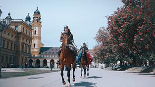 Ein Video von Reitern im M&uuml;nchner Hofgarten ist Teil von Kratzers Inszenierung.