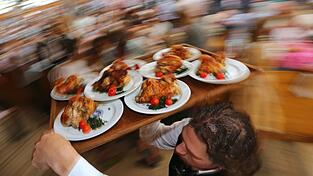 Ein Kellner trägt auf dem Oktoberfest Hendl (Hähnchen) auf einem Tablett. Ein Kellner trägt auf dem Oktoberfest Hendl (Hähnchen) auf einem Tablett.