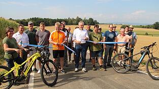 Mit drei Schnitten durch ein blau-wei&szlig;es Band gaben Eichendorfs B&uuml;rgermeister Josef Beham (mit Scheren, v. l.) , Landrat Werner Bumeder und Landaus Zweiter B&uuml;rgermeister Martin Aigner den Radweg frei. Anschlie&szlig;en wurde mit allen Projektbeteiligten und Anwohnern angesto&szlig;en.