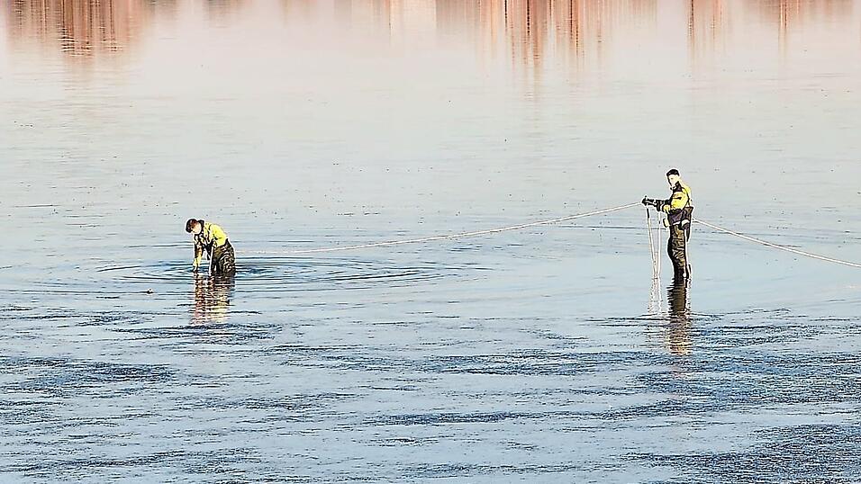 Mit Wathosen, Leinensicherung und Rettungsboot n&auml;hern sich Feuerwehrkr&auml;fte und ein J&auml;ger dem ersch&ouml;pften Tier.