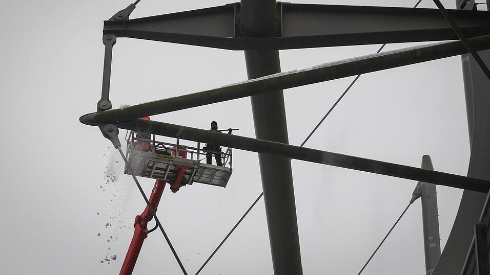 Arbeiter mit einem Hubsteiger entfernen Eis und Schnee von den Tr&auml;gern des Stadiondachs in Hamburg.