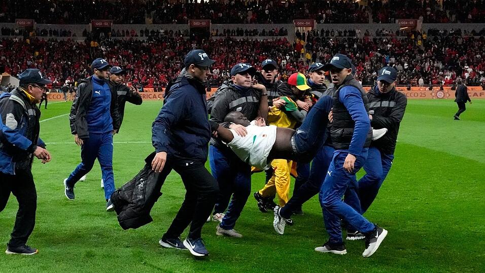 Ein auf den Platz gest&uuml;rmter Anh&auml;nger des Senegals wurde von Sicherheitskr&auml;ften weggetragen. (Archivbild)