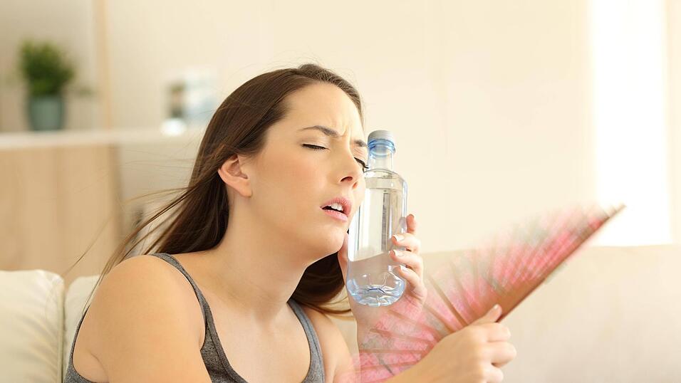 Mit kühlem Wasser und Fächer versucht eine Frau, die Hitze zu vertreiben. Mit kühlem Wasser und Fächer versucht eine Frau, die Hitze zu vertreiben.